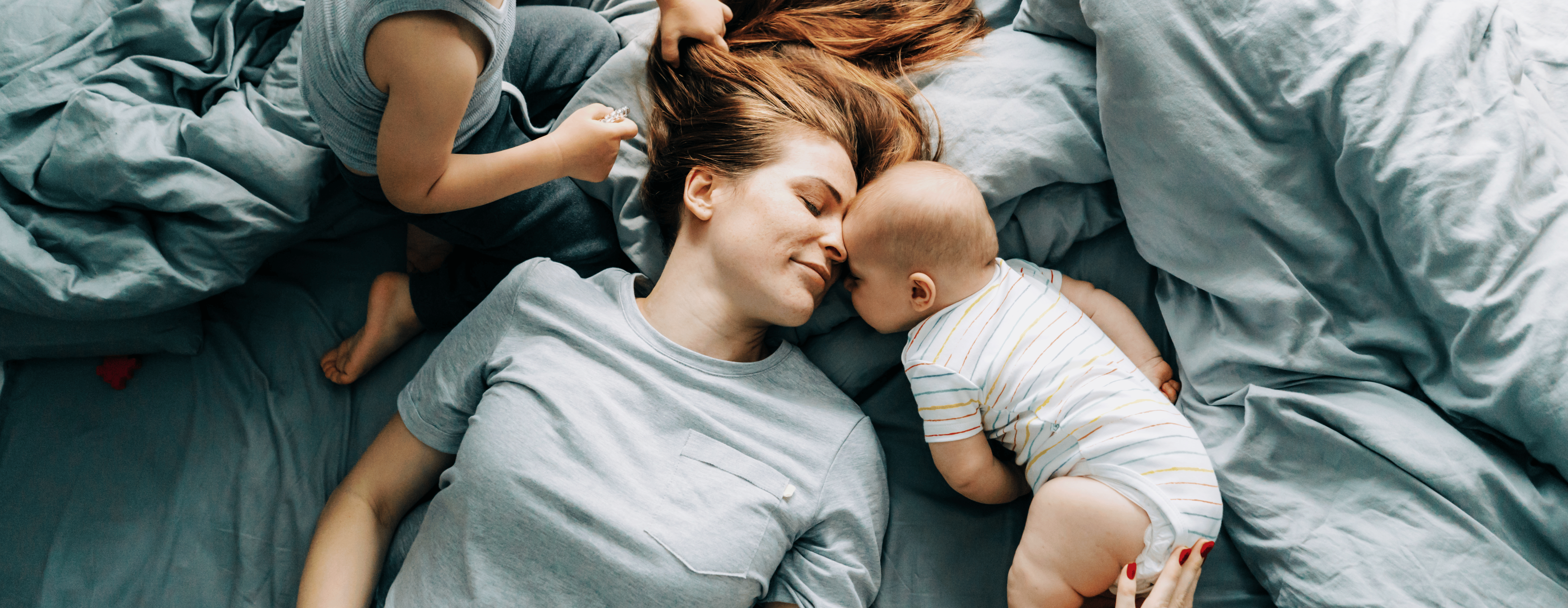 mom kissing baby, mom and kids on bed