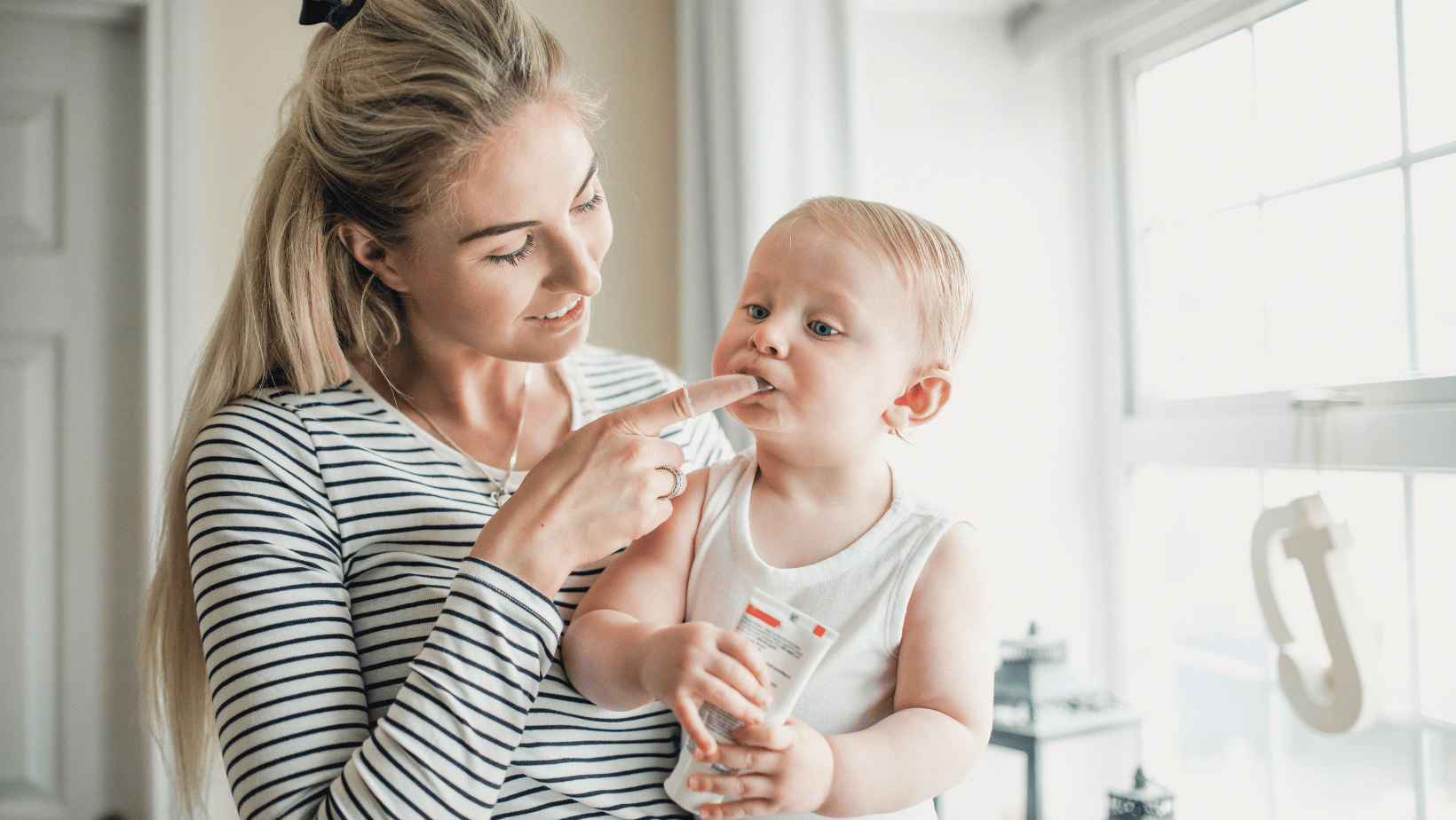 Mom applies teething gel to child's gums